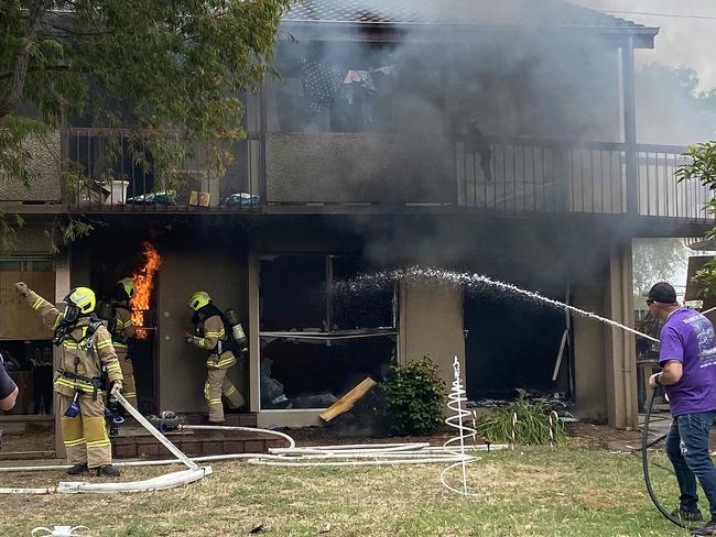 Fireflighters at a blaze at a block of units on Ballarat Rd, North Geelong get some help from a person with a garden hose. Photo: Laura Sexton