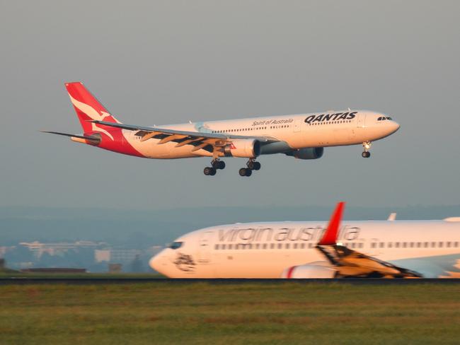 A Qantas Airbus A330-303 plane, registration VH-QPB, coming into land from the south on the main runway of Sydney Kingsford-Smith Airport as flight QF128 from Hong Kong. In the foreground is a Virgin Australia Boeing B737-8FE plane, registration VH-YFZ, taxiing before departure as flight VA1528 to Hobart.  This image was taken from Mill Stream Lookout, Botany Bay on a sunny morning at sunrise on 30 March 2024.27 October 2024Kendall HillPhoto - iStock