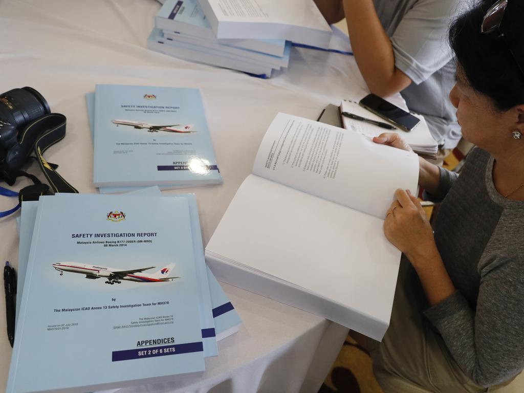 Copies of the final investigation report on missing flight MH370 are offered to the media. Picture: AP