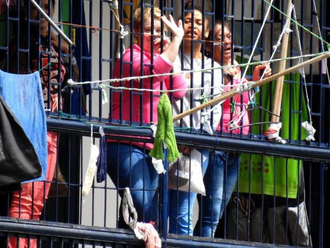 Cassie Sainsbury signals to photographers from inside the jail where she is being held in Bogota, Colombia. Picture: Nathan Edwards