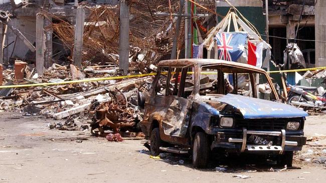 Forensic police officers and the wreckage of a car at scene of the Sari Club nightclub blast in Kuta.