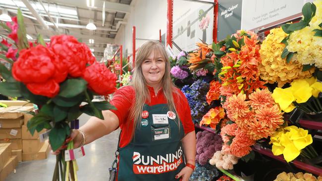 Bunnings team member Amanda Dolan holds plastic flowers in the newly introduced flower section. (AAP IMAGE / Angelo Velardo)