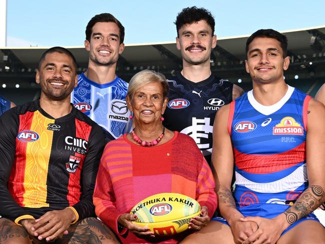 MELBOURNE, AUSTRALIA - MAY 13:  (Back Row L-R) Jayden Davey of the Bombers, Tyson Stengle of the Cats, Jy Simpkin of the Kangaroos, Zac Williams of the Blues, Karl Amon of the Hawks, Rhyan Mansell of the Tigers, (Front Row L-R) Kysaiah Pickett of the Demons, Bradley Hill of the Saints, Aunty Pam Pedersen, Yorta Yorta Elder and daughter of Sir Doug Nicholls, Jamarra Ugle-Hagan of the Bulldogs and Bobby Hill of the Magpies pose for a photo during the 2024 Sir Doug Nicholls Round Launch at Melbourne Cricket Ground on May 13, 2024 in Melbourne, Australia. (Photo by Quinn Rooney/Getty Images)