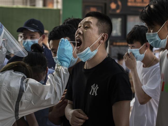 BEIJING, CHINA - JUNE 16: A Chinese man who has had contact with the Xinfadi Wholesale Market or someone who has, reacts as a Chinese epidemic control worker performs a nucleic acid test for COVID-19 at a testing center on June 16, 2020 in Beijing, China. Authorities are trying to contain the outbreak linked to the Xinfadi wholesale food market, Beijing's biggest supplier of produce and meat. Several neighborhoods have been locked down and at least two other food markets were closed, as tens of thousands of people are being urged to get tested for COVID-19 at sites set up around the city. The outbreak has triggered fears of a second wave of infection after 56 straight days with no domestically transmitted cases in the capital. More than 8,000 vendors and staff at Xinfadi have already been tested, according to city officials, who are using contact tracing to reach an estimated 200,000 people who have visited the market since May 30. (Photo by Kevin Frayer/Getty Images)