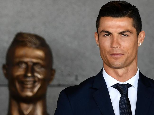 Portuguese footballer Cristiano Ronaldo stands with his new statue in the background.