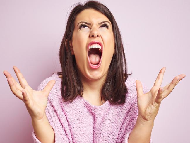 Young beautiful brunette woman wearing a sweater over pink isolated background crazy and mad shouting and yelling with aggressive expression and arms raised. Frustration concept.