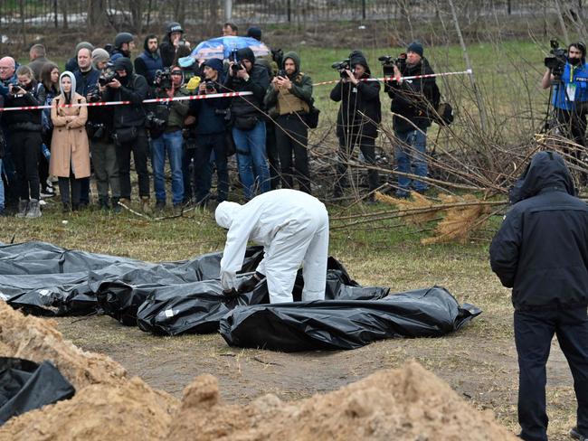 Members of the press work as Ukrainian investigators line up body bag during the exhumation of a mass grave in the town of Bucha. Picture: AFP