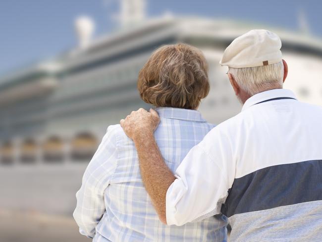 Senior Couple On Shore Facing and Looking at Docked Cruise Ship. seniors and retirees travel, holidays, generic