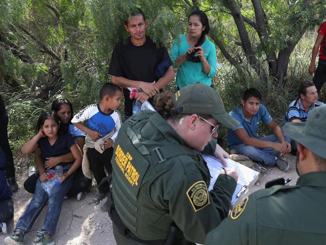 Central American asylum seekers wait as US Border Patrol agents take groups of them into custody  near McAllen, Texas. The families were sent to a US Customs and Border Protection  center for possible separation.