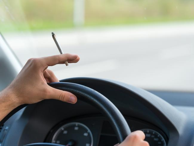 Close-up of a men driving and smoking joint