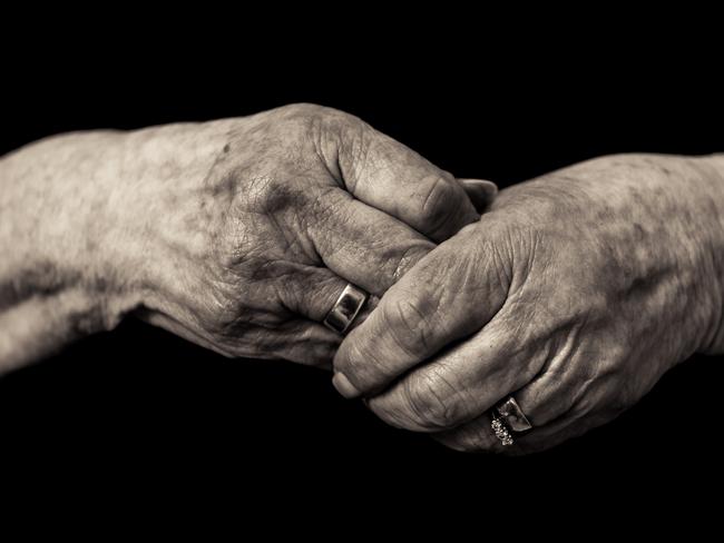 Black and white image of an older lady's hands clasped in grief wearing her late husbands wedding ring. Concept of loss, mourning and loneliness in old age. ISTOCK