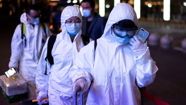 Passengers in hazmat suits at a railway station in China’s Wuhan, where the coronavirus began. Picture: AFP