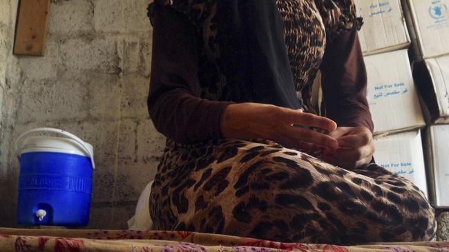 FILE - In this file photo taken Wednesday, Oct. 8, 2014, a 15-year-old Yazidi girl captured by the Islamic State group and forcibly married to a militant in Syria sits on the floor of a one-room house she now shares with her family after escaping in early August, while speaking in an interview with The Associated Press in Maqluba, a hamlet near the Kurdish city of Dahuk, 260 miles (430 kilometers) northwest of Baghdad, Iraq. Hundreds of women have been captured by the group, enslaved and sold, many have been subjected to sexual violence and others have been stoned for adultery. (AP Photo/Dalton Bennett, File)