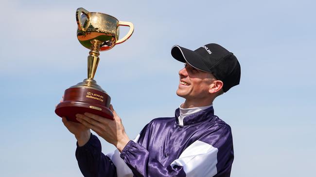 Jye McNeil celebrates with the trophy after winning the Melbourne Cup.