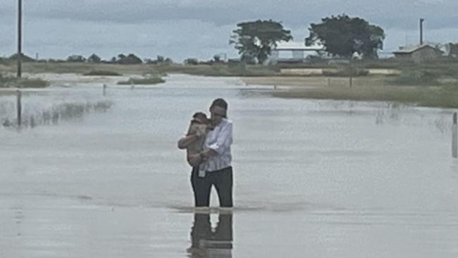 Paula McKinlay wades through filthy floodwaters with Gunja, one of the dogs left behind when Burketown residents had to be evacuated as the floods surged across the Gulf community. Picture: Supplied