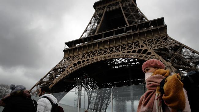 A woman wearing a mask walks pasts the Eiffel Tower, which was closed after the French government banned all gatherings of over 100 people. Picture: AP