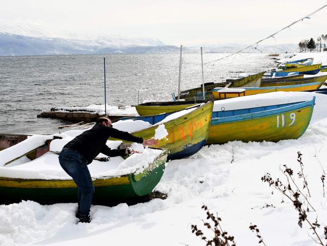 A fisherman cleans the snow from his boat on the shore of Ohrid Lake, in Pogradec, southeast Albania, on February 27, 2018. Dubbed “The Beast from the East,” Europe was seized on February 27 with an icy cold originating from Siberia, which has already been responsible for twenty deaths in four days. Picture: AFP