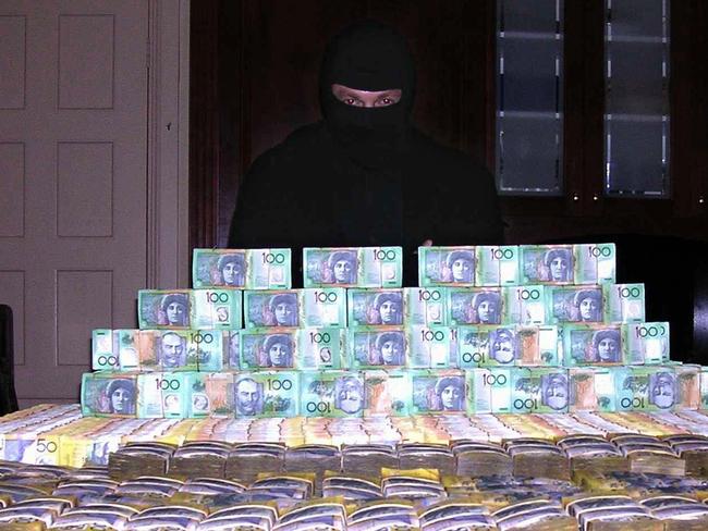A man in a balaclava said to be surfer Shayne Hatfield poses with a huge pile of cash in a 2005 copy photo. The photo was found when police from Operation Mocha raided his house and arrested him. Hatfield was allegedly part of a cocaine trafficking syndicate.