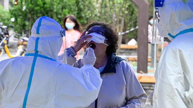 A health worker takes a swab sample from a woman to be tested for Covid-19 at a makeshift testing site in Beijing. Picture: AFP