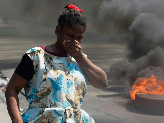 A woman walks past burning tires during a demonstration following the resignation of its Prime Minister Ariel Henry, in Port-au-Prince, Haiti, on March 12, 2024. A political transition deal in Haiti marks a key step forward for the violence-ravaged country but far more needs to be done, with some experts warning the situation could deteriorate further. (Photo by Clarens SIFFROY / AFP)