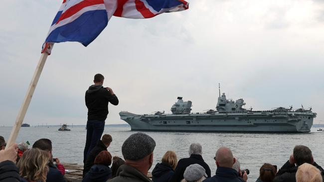 People watch from the shore as HMS Queen Elizabeth aircraft carrier leaves Portsmouth.