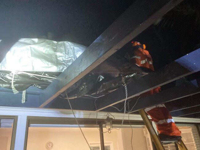 Volunteers from the Pittwater/Warringah Unit of the SES work to cover a leaking roof with a tarpaulin. SES Pittwater/Warringah