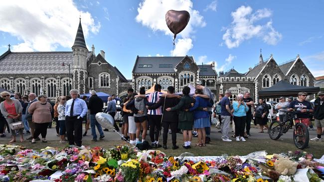 A group of students sing in front of flowers left in tribute to victims at the Botanical Garden in Christchurch. Picture: Anthony Wallace/AFP)