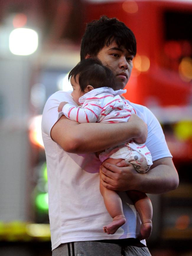 A resident and a baby flee the apartment tower. Picture: Andrew Henshaw