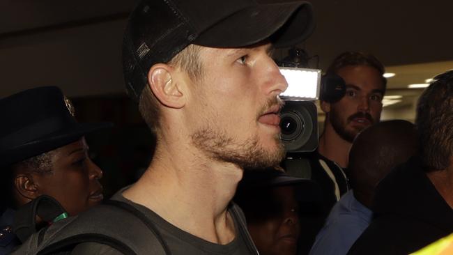 Australia's cricket player Cameron Bancroft, is escorted by police officers to the departure area at OR Tambo International airport in Johannesburg, South Africa, Wednesday, March 28, 2018. Steve Smith, vice-captain David Warner and batsman Cameron Bancroft are being sent home from South Africa for ball-tampering in the third Test in Cape Town. (AP Photo/Themba Hadebe)