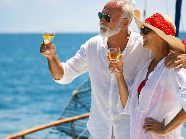 Closeup side view of mid 60's couple enjoying a sailing cruise during  summer vacation at seaside. They are leaning on deck railing and enjoying the view of the sea and horizon. rich wealthy generic