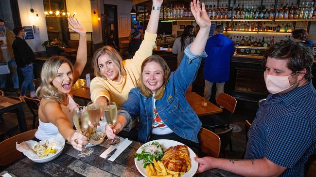 First customers at The Local pub in Port Melbourne Tess Fisher, Carla Snellen and Steph Parsons, are served up by Sam Heathcote. Picture: Mark Stewart