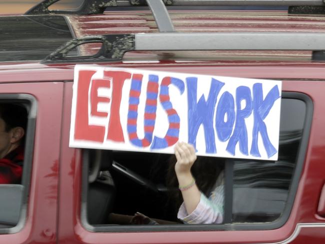 A sign is held out of a car as protesters drive past the Tennessee state capitol to speak out against the state's handling of the COVID-19 outbreak Sunday, April 19, 2020, in Nashville, Tenn. Tennessee is under a stay-at-home order due to the coronavirus outbreak except for essential workers. (AP Photo/Mark Humphrey)