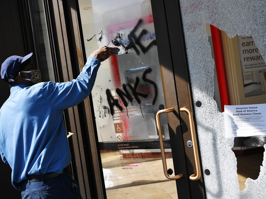 A worker cleans up the front of a damaged bank in Washington, DC. Picture: MANDEL NGAN / AFP