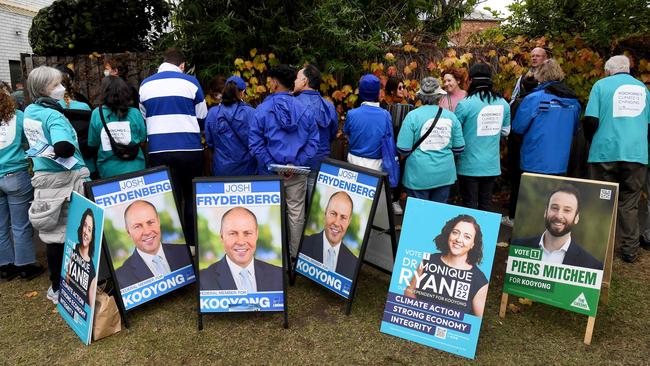 Volunteers handout how-to-vote cards while people queue at a pre-polling centre in Melbourne on May 17 in Kooyong, the blue-ribbon seat lost by Josh Frydenberg to independent Monique Ryan.