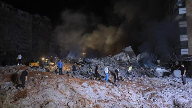 People and first responders stand on the rubble of a builiding destroyed in an Israeli air strike in the Haret Hreik neighbourhood of Beirut's southern suburbs. Picture: AFP