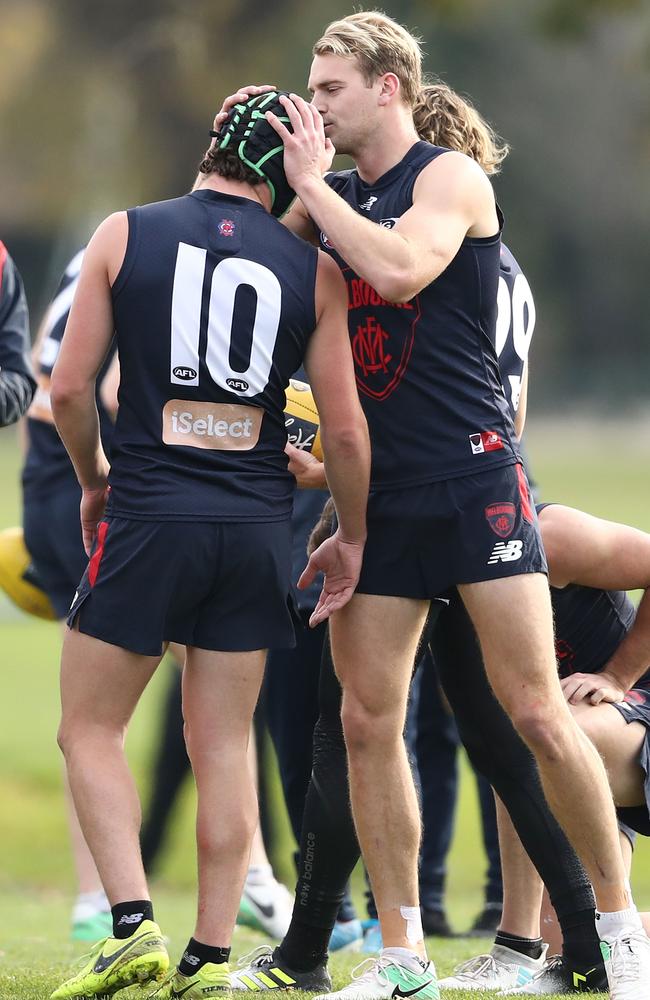 Jack Watts helps Angus Brayshaw with his headgear at Melbourne training.