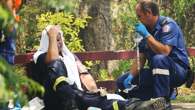 An exhausted fireman who battled a fire at Kurri Kurri in the Hunter Region is treated by paramedics. Picture: Peter Lorimer