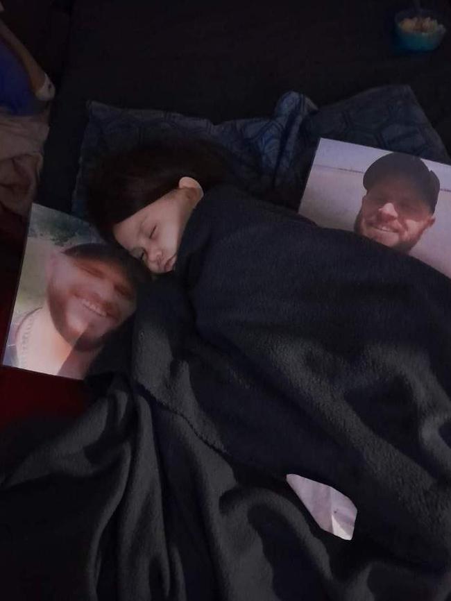 Six-year-old Charlie pictured sleeping next to photos of her dad. Picture: Supplied