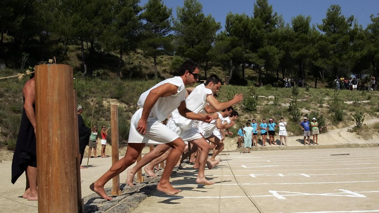 Barefooted athletes run a 100-meter race in the ancient stadium of Nemea on June 21, 2008 during the revival of the ancient Nemean Games. The 2,300-year-old Nemean Games, one of the direct ancestors of the modern Olympic Games, take place every four years, like the the modern Olympics. AFP PHOTO / Louisa Gouliamaki