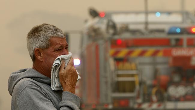 A resident watches the progress of bushfires near houses in Old Bar, NSW on Saturday.