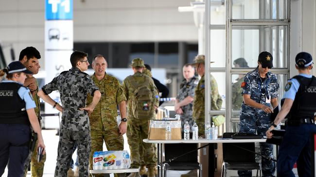 Personnel from the NSW Police Force, Australian Royal Navy and Australian Defence Force wait to help returning travellers at Sydney airport. Picture: AAP.