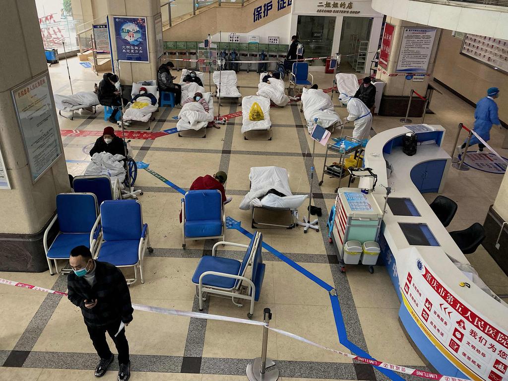 A man stands in front of a cordoned-off area, where Covid-19 patients lie on hospital beds, in the lobby of the Chongqing No. 5 People's Hospital in China. Picture: AFP