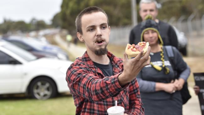 A passerby mocks the vegan protestors by eating a meat pie in front of them. Picture: Alan Barber