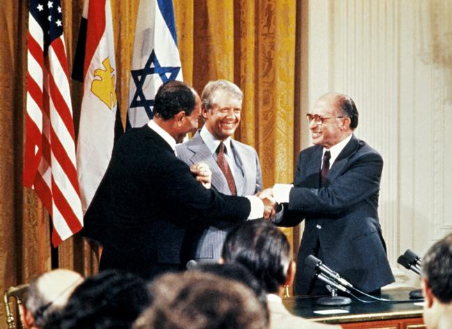 Egypt's Anwar Sadat (L) and Israel's Menachem Begin (R) shake hands at the White House with then US president Jimmy Carter in September 1978 after a ceremonial signing of one of the Camp David accords