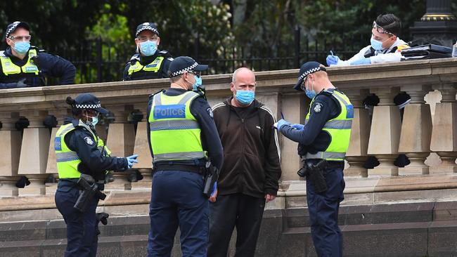 Police check details of residents in Melbourne’s CBD on August 9, 2020, as the city struggles to cope with a COVID-19 coronavirus outbreak. (Photo by William WEST / AFP)