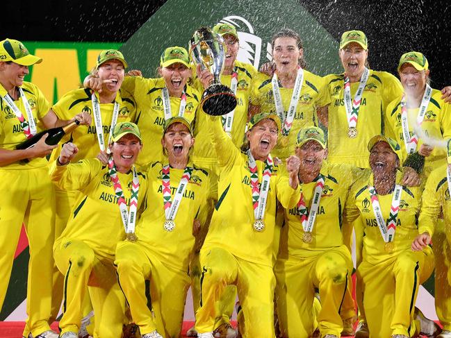 (FILES) In this file photo taken on April 03, 2022 Australia's captain Meg Lanning (C) holds the trophy as team celebrate their win after the Women's Cricket World Cup final match between England and Australia at Hagley Park Oval in Christchurch on April 3, 2022. - Waiting tables in her local cafe and hanging out with friends and family helped rekindle Meg Lanning's love of cricket and intensified her drive to steer top-ranked Australia to another Twenty20 World Cup title this month.The decorated women's skipper took a indefinite months-long hiatus in 2022 after an intense few years, sparking fears she would not return. (Photo by Sanka VIDANAGAMA / AFP)