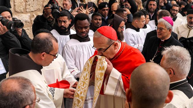 Latin Patriarch of Jerusalem Pierbattista Pizzaballa (C) kisses another clergyman's robes as he arrives for Christmas Eve celebrations in the occupied West Bank. Picture: Hazem Bader/AFP