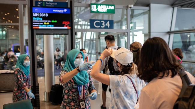 A Malaysia Airlines hostess checks the temperature of Chinese passengers before they board a flight to Beijing at Kuala Lumpur International Airport. Picture: AFP