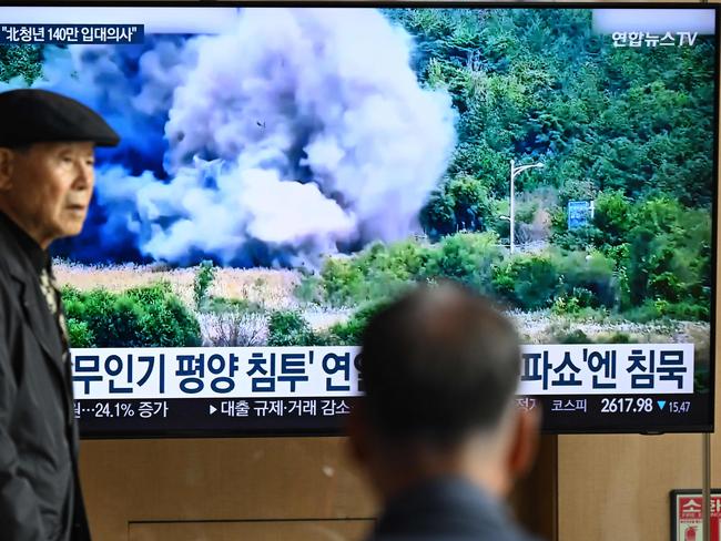 A man walks past a television screen showing a news broadcast with footage of an explosion on a road connecting North and South Korea on October 15, 2024.