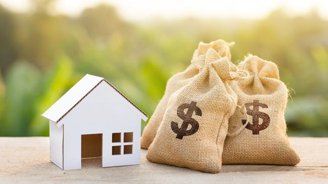 Loan and House concept. Money bags put near house on woodle desk at sunset and green nature background